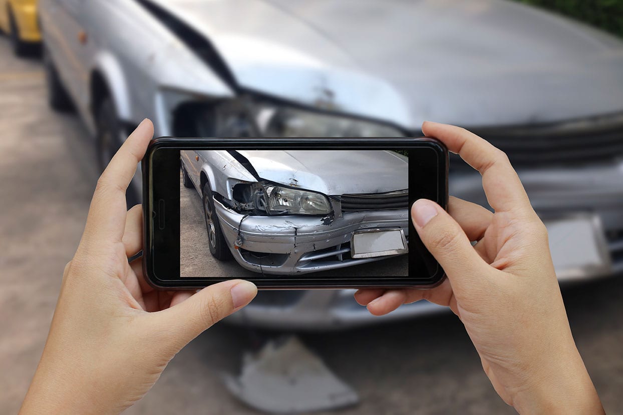 photo of a car accident injury victim documenting their damaged vehicle for their car accident claim
